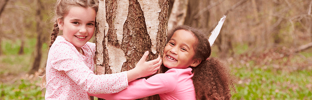 Two girls hugging a tree