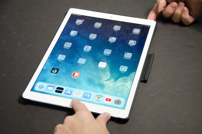 iPad with hands pressing both the power button and the home button simultaneously