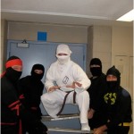 4 black ninjas holding two swords with white ninja on the swords