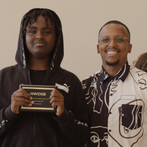 grad coach with student holding award